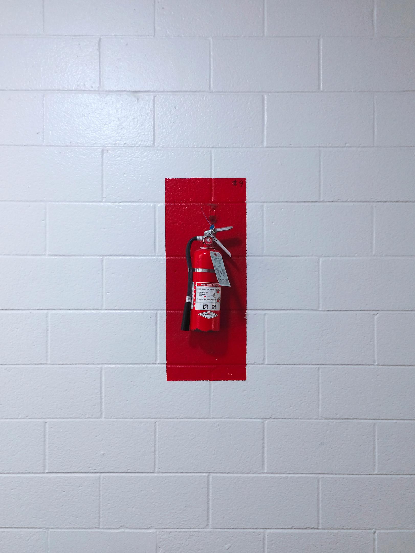 Fire extinguisher mounted on a wall in a workplace.