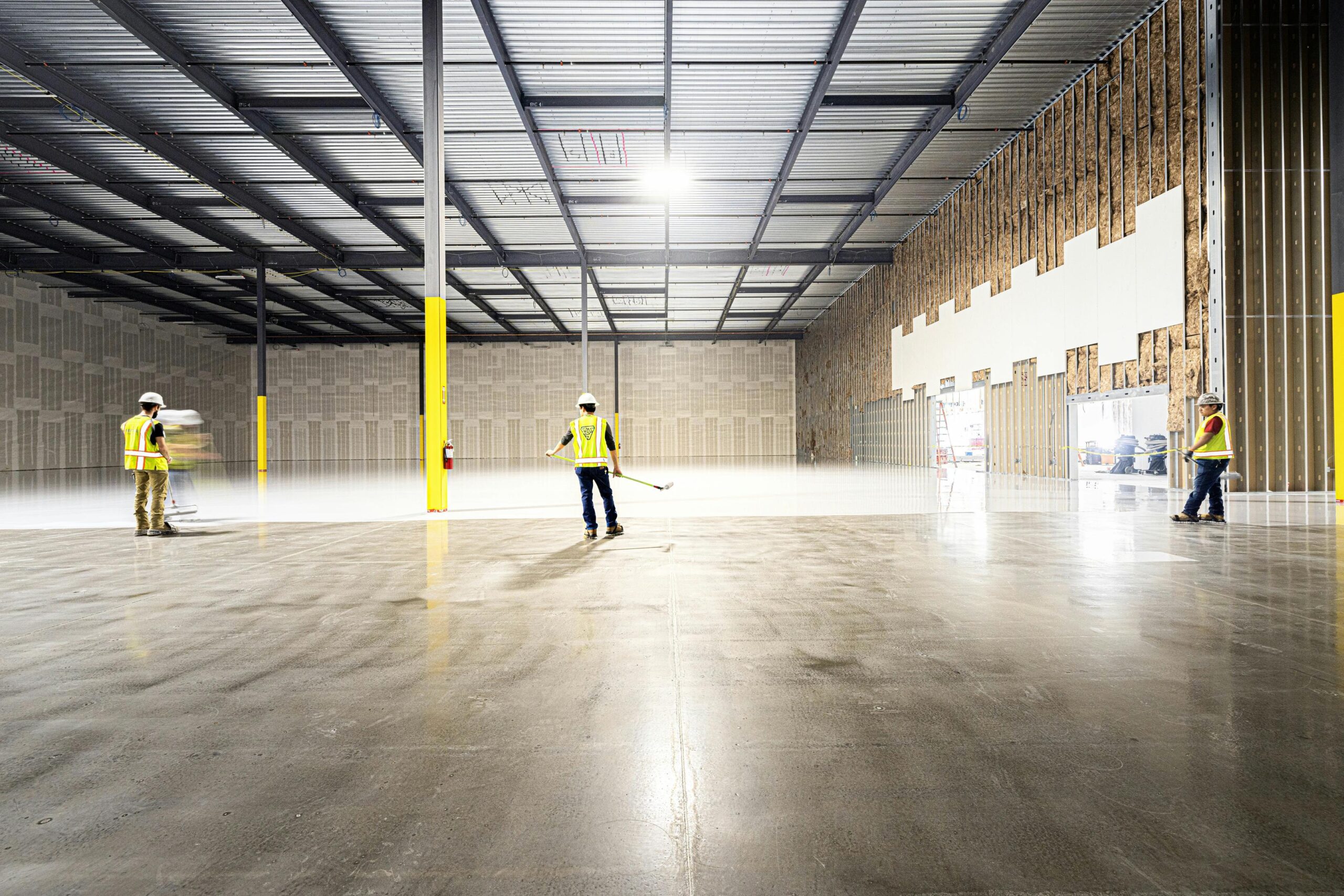 Workers inspecting safety conditions inside an industrial warehouse.